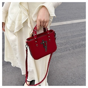 Detail of red PU gothic bag with metal cross, chain, and studs held by model