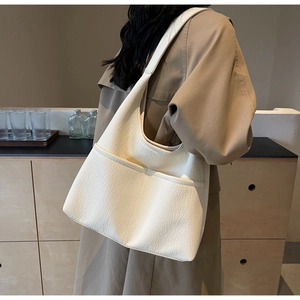 Detail showing the creamy white hobo bag with textured lychee grain and front pockets