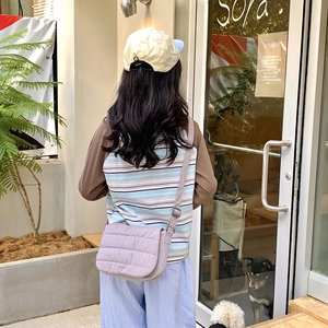 Outdoor lifestyle shot of a light purple quilted crossbody bag with adjustable wide strap