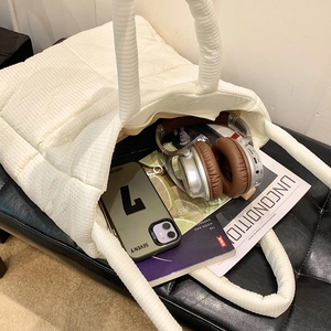 Dettaglio della borsa tote bianca trapuntata che mostra lo spazio interno per cuffie e libri