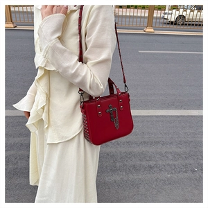 Detail view of red PU leather handbag with punk silver rivets and cross pendant charm