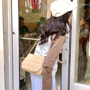 Street style view of beige quilted nylon crossbody bag with matching shoulder strap