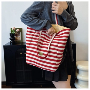 Detail of red and white striped canvas tote bag with handmade label worn by model