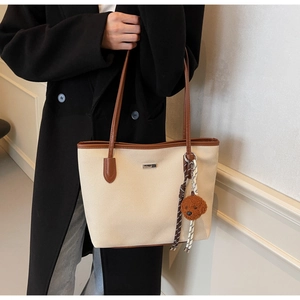 Detailed shot of canvas tote bag with brown leather trim and cute puppy charm on model