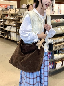 Detailed view of brown hobo crossbody bag in matte suede fabric with a cute bear charm