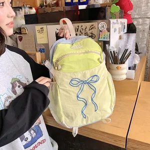 Detail eines gelben Nylon-Rucksacks mit blauer Schleifenstickerei und seitlichem Netz