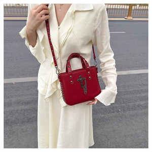 Detail of red PU crossbody bag with black metallic cross and gothic rivet straps