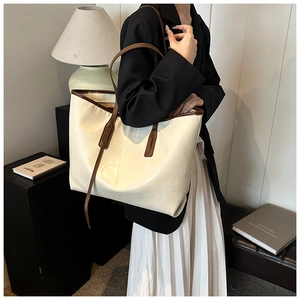 Detail of cream white tote bag with geometric texture and brown straps on a model