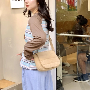 Close-up of beige quilted fabric shoulder bag with padded texture and adjustable strap