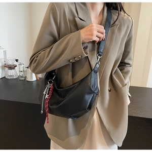 Detail of black semi-moon PU leather crossbody bag with silver chain and woven rope charm