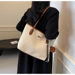 Detail view of a large cream woven tote bag with brown leather straps on a model