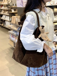 Detail of dark brown corduroy tote bag with cute plush dog pendant accessory