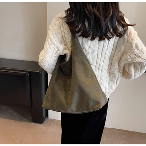 Detail view of olive green suede tote bag showing soft texture on a shoulder carry