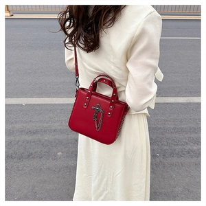 Detail of red PU crossbody bag featuring silver studs and gothic cross pendant charm