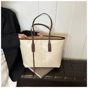 Detail of minimalist beige PU leather tote with dark brown handles and patchwork texture