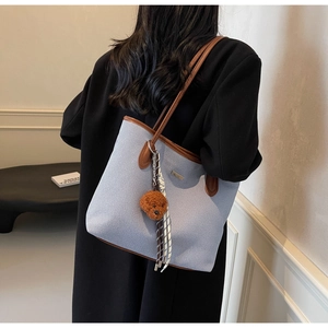Detail of light blue canvas tote bag with brown leather trim and cute puppy charm accessory