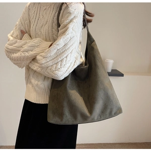 Detailed texture of olive green suede tote bag shown on a white knitted sweater