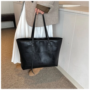 Detail of black PU leather tote bag featuring unique geometric patchwork texture design