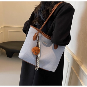 Detail of light blue canvas tote with brown leather trim and cute teddy bear pendant