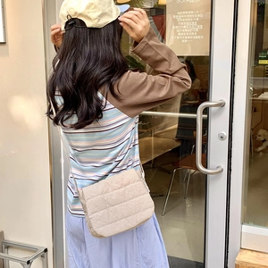 Beige quilted crossbody bag in textured nylon fabric styled with a casual autumn outfit