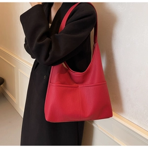 Detail of red large capacity shoulder bag with soft lychee texture leather on black coat