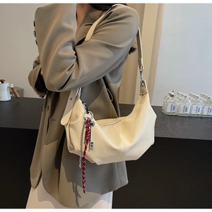 Detail of cream PU leather crossbody bag with silver chain and red woven charm