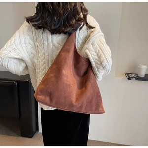 Detail of a large brown suede tote bag on shoulder with cozy autumn knitwear outfit