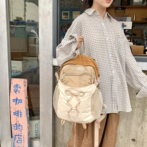 Detail eines Khaki-Patchwork-Rucksacks mit gestickter brauner Schleife und Netz-Seitentasche