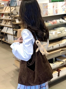 Detail view of brown corduroy shoulder bag with soft plush dog keychain accessory