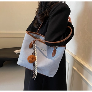 Detail of light blue tote bag with brown leather trim and cute teddy plush charm accessory