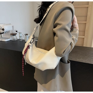 Detail of cream PU crossbody bag with red woven rope and metal carabiner charm