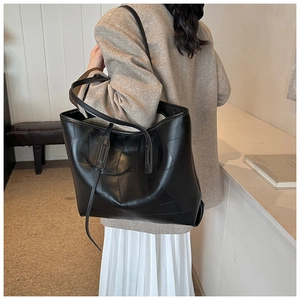 Detail shot of the large black tote bag featuring geometric stitching and long side ribbons