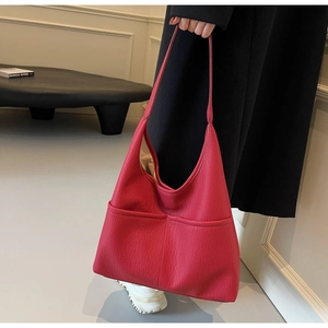 Detail of red pebbled leather tote bag with functional front pockets and soft texture
