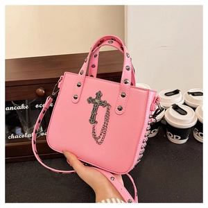 Pink PU leather handbag with silver rivets and gothic cross charm in cafe setting