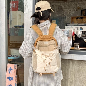 Detail eines farblich abgesetzten Rucksacks mit Schleifenstickerei und Netztaschen