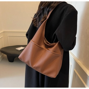 Close-up of caramel brown tote bag showing litchi texture leather and double front pockets
