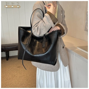 Detail of black PU leather tote bag with square stitching pattern on a model