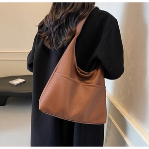 Brown litchi texture PU leather tote bag shown on a model in a minimal interior setting