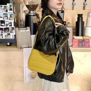 Close-up of mustard yellow quilted nylon shoulder bag styled with a chic autumn outfit