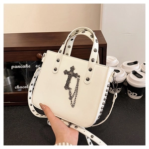 White PU leather tote bag with black studs and cross pendant in a cafe setting