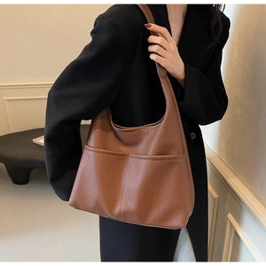 Detail of a brown PU leather shoulder bag with lychee texture on a business model