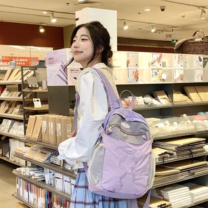 Detailansicht eines lilafarbenen Stoffrucksacks mit grauen Netztaschen und Schleifennähten