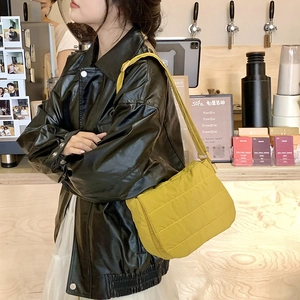 Close-up of yellow quilted nylon crossbody bag with flap and wide shoulder strap