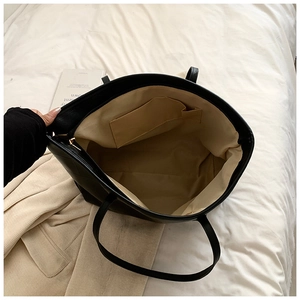 Overhead view of a black faux leather tote bag with beige lining and internal pocket