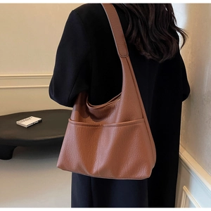 Detail of brown litchi pattern PU leather hobo bag with front dual pockets on model