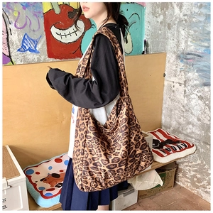 Detail of leopard print canvas shoulder bag with wide strap on model in urban style