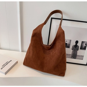 Detail of brown suede tote bag with leather strap and minimalist trapezoid design