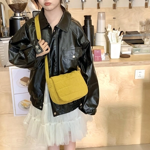 Close-up of a yellow quilted crossbody bag showing soft puffer texture and street style