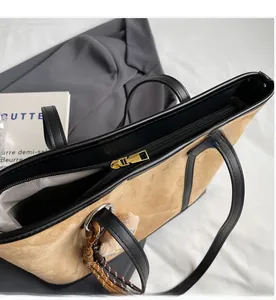 Detail view of smooth golden zipper and herringbone lining on beige suede tote bag