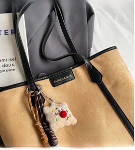 Close-up of camel PU leather tote bag with black handles and fashion brand label